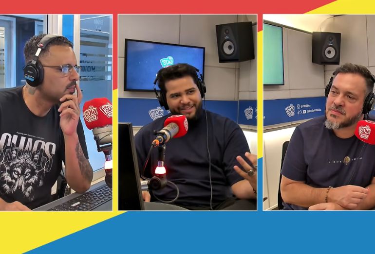 Guto TV sorridente durante entrevista no estúdio da FM O DIA, falando ao microfone com fones de ouvido.